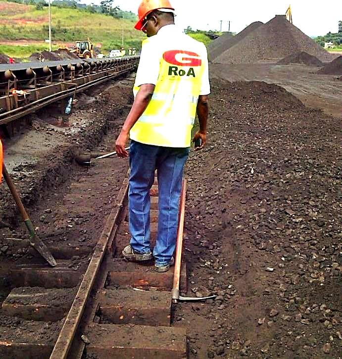 Agent GROA réglant la voie devant les tas de minerai